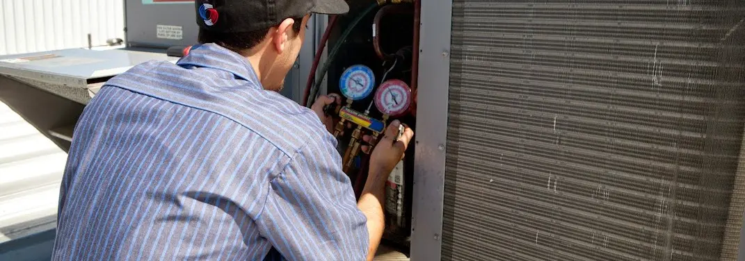HVAC technician servicing a condenser unit in Martin
